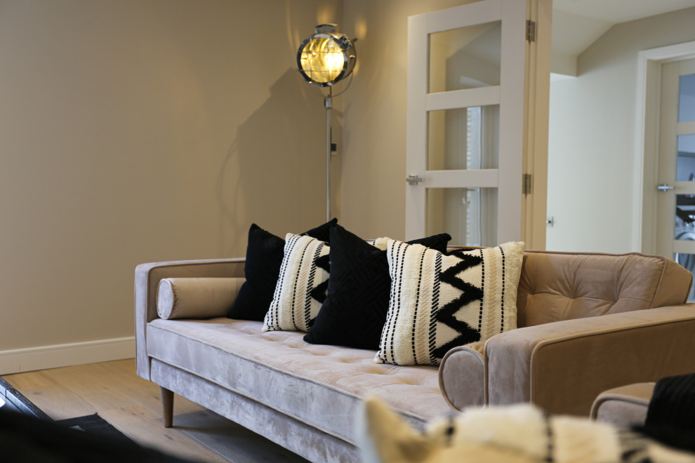 Modelo de salón contemporáneo de tamaño medio con paredes beige, suelo de madera clara, televisor colgado en la pared y suelo beige