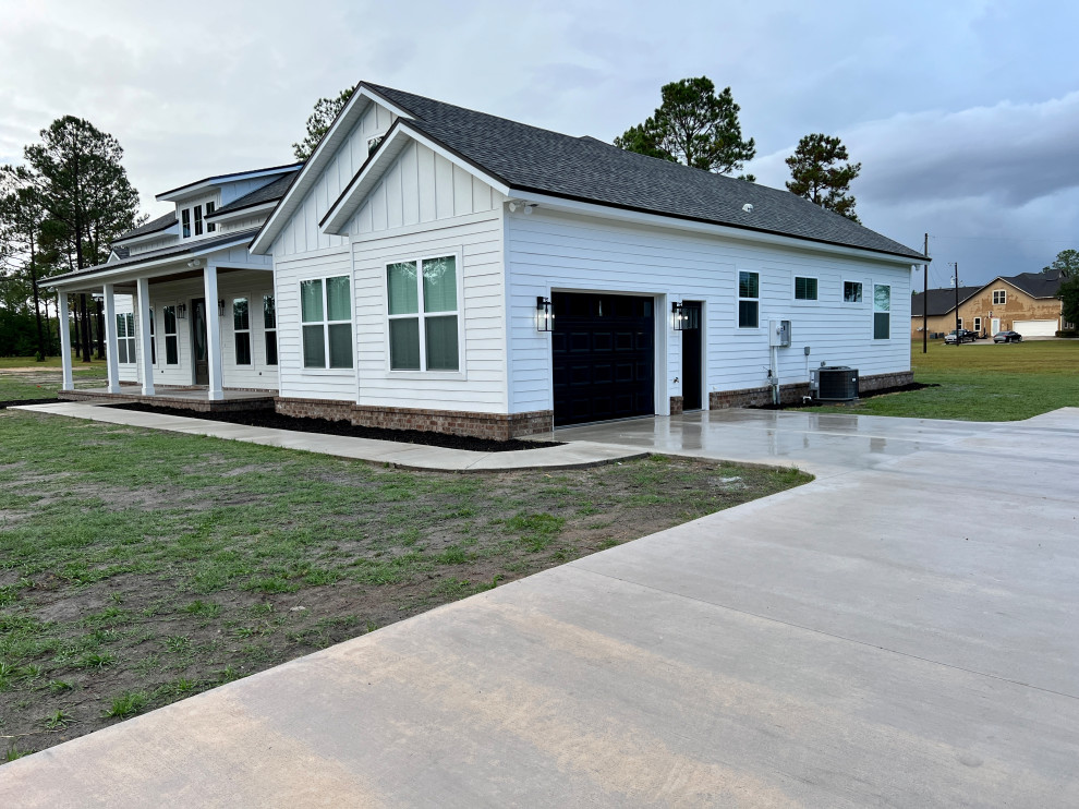 This is an example of a white farmhouse bungalow detached house in Jacksonville with a black roof.