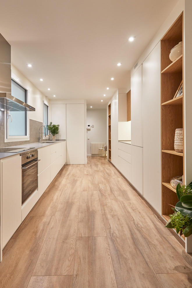 Large modern kitchen in Barcelona with a built-in sink, flat-panel cabinets, integrated appliances and grey worktops.