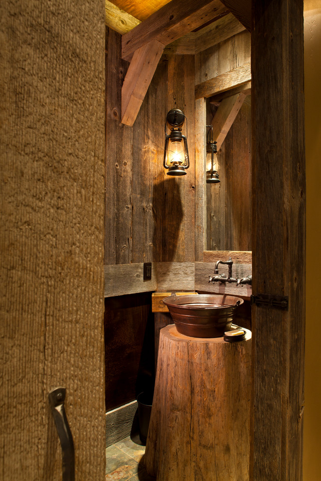 This is an example of a small country powder room in Denver with brown walls, a vessel sink and slate floors.