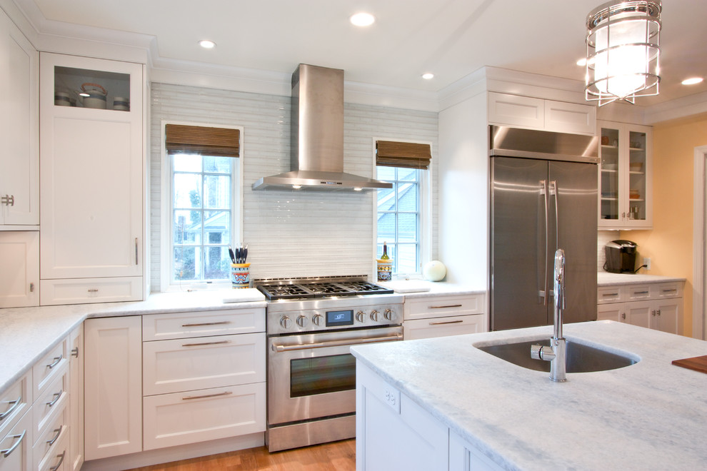 Example of a transitional medium tone wood floor eat-in kitchen design in Newark with an undermount sink, recessed-panel cabinets, white cabinets, glass tile backsplash, stainless steel appliances, white backsplash and an island