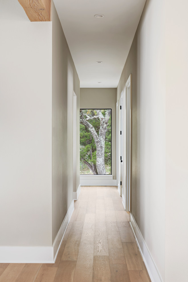 Design ideas for a mid-sized country hallway in Austin with grey walls, light hardwood floors and brown floor.