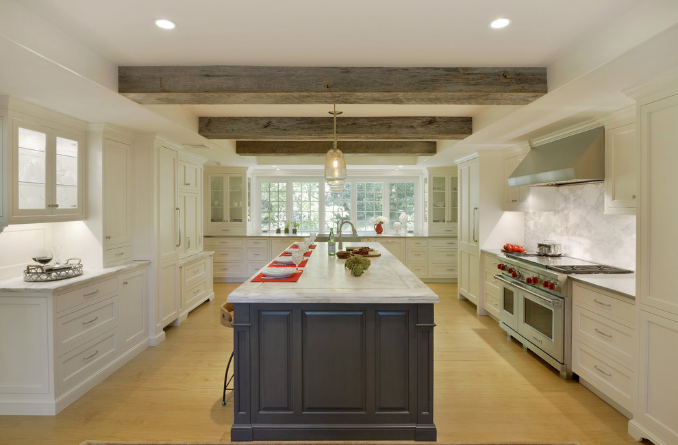 Expansive traditional u-shaped eat-in kitchen in New York with a farmhouse sink, recessed-panel cabinets, white cabinets, marble benchtops, grey splashback, marble splashback, panelled appliances, light hardwood floors, with island, beige floor and multi-coloured benchtop.