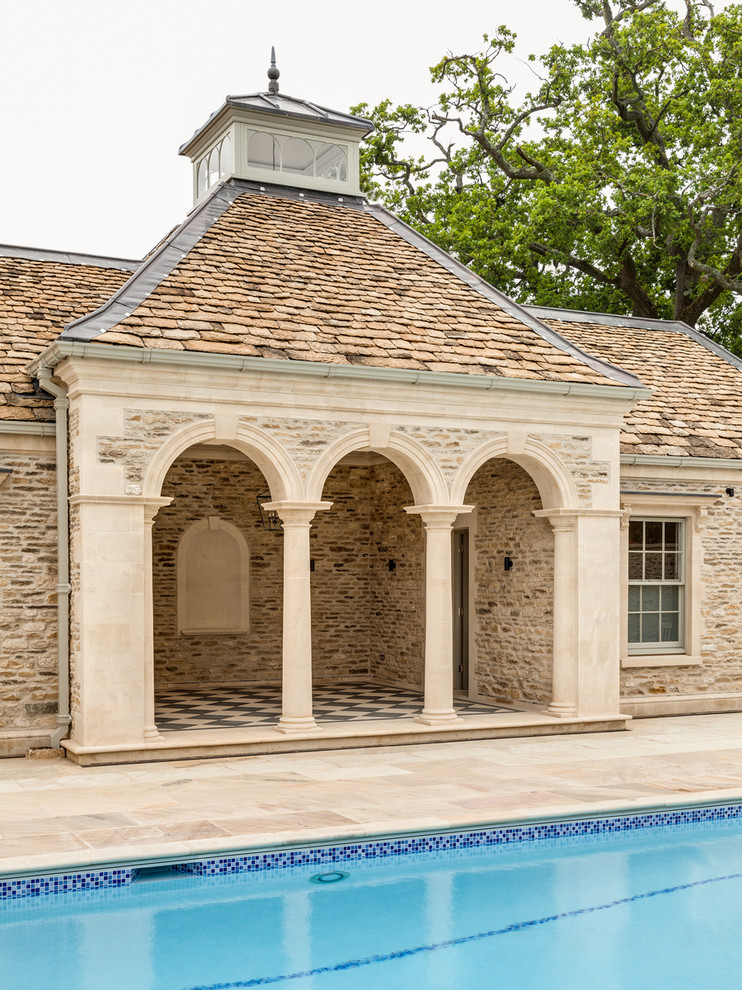 Traditional rectangular pool in Gloucestershire with a pool house and natural stone pavers.