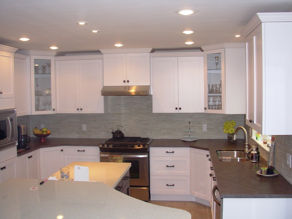 Kitchen - mid-sized transitional u-shaped laminate floor and beige floor kitchen idea in Vancouver with a double-bowl sink, shaker cabinets, white cabinets, solid surface countertops, beige backsplash, porcelain backsplash, stainless steel appliances and a peninsula