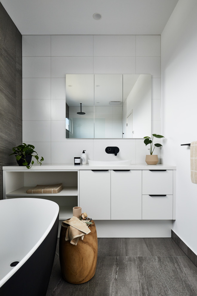 Inspiration for a mid-sized contemporary kids bathroom in Melbourne with white cabinets, a freestanding tub, white tile, multi-coloured walls, grey floor, an open shower, white benchtops and a single vanity.