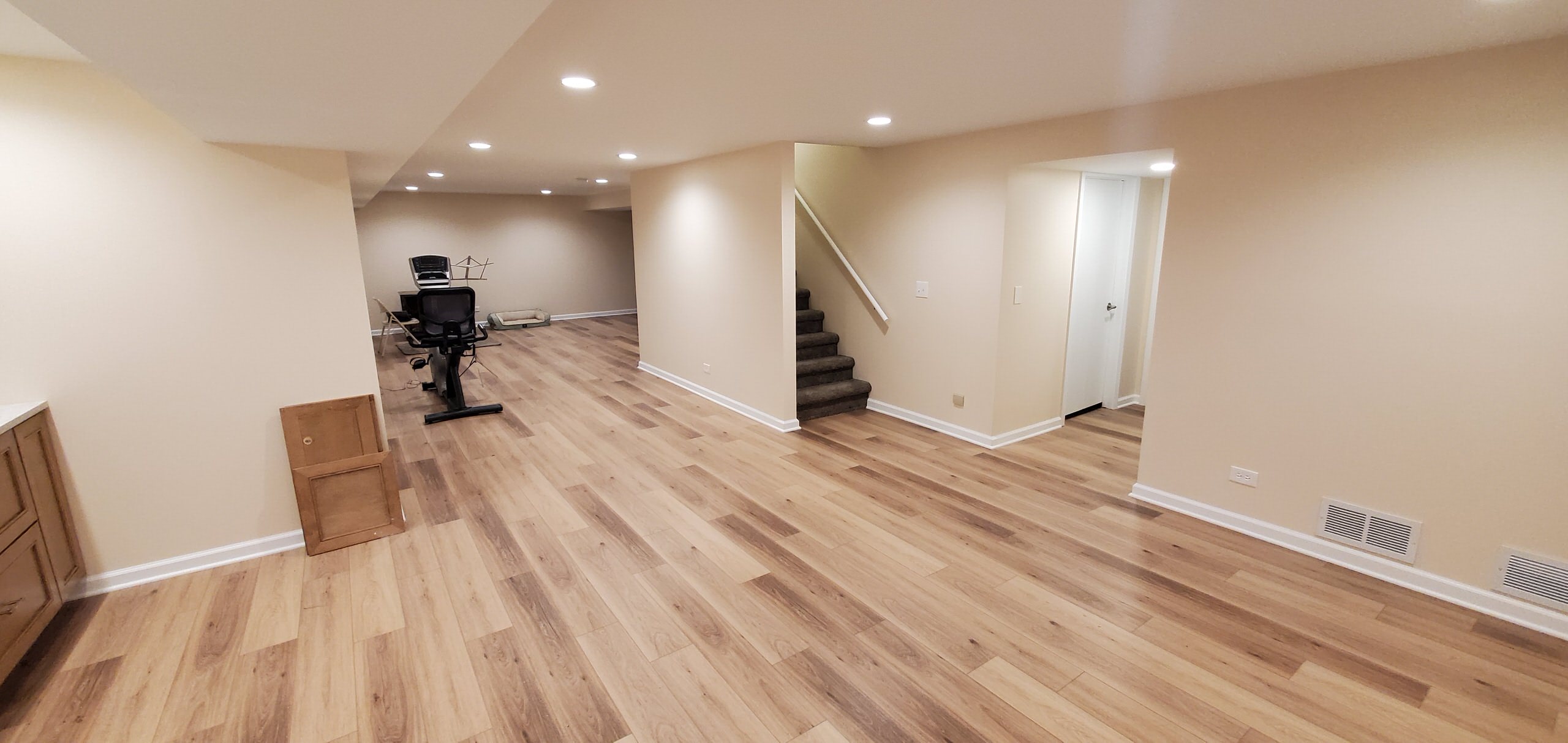 Fully remodeled 1970s finished basement with luxury vinyl plank flooring and can