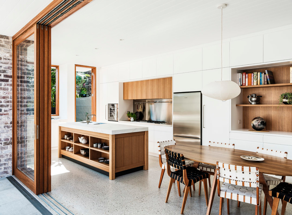 Photo of a large contemporary galley eat-in kitchen in Sydney with a drop-in sink, flat-panel cabinets, white cabinets, quartz benchtops, metallic splashback, metal splashback, stainless steel appliances, concrete floors, with island, grey floor and white benchtop.