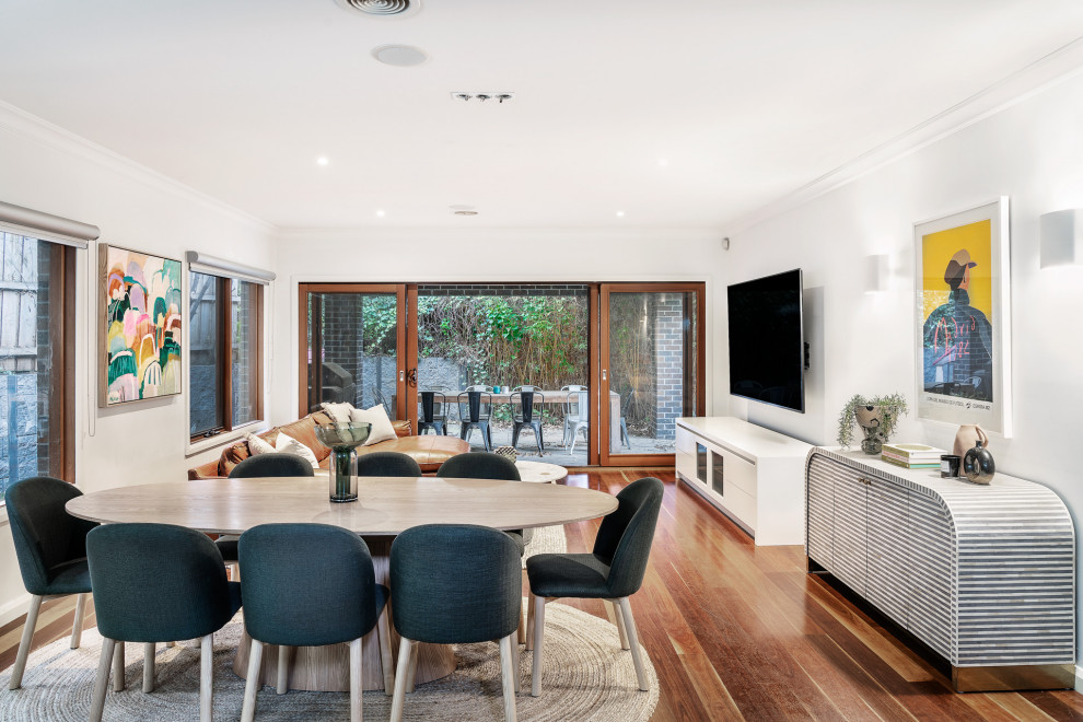 Contemporary open plan dining in Melbourne with white walls, medium hardwood floors and brown floor.