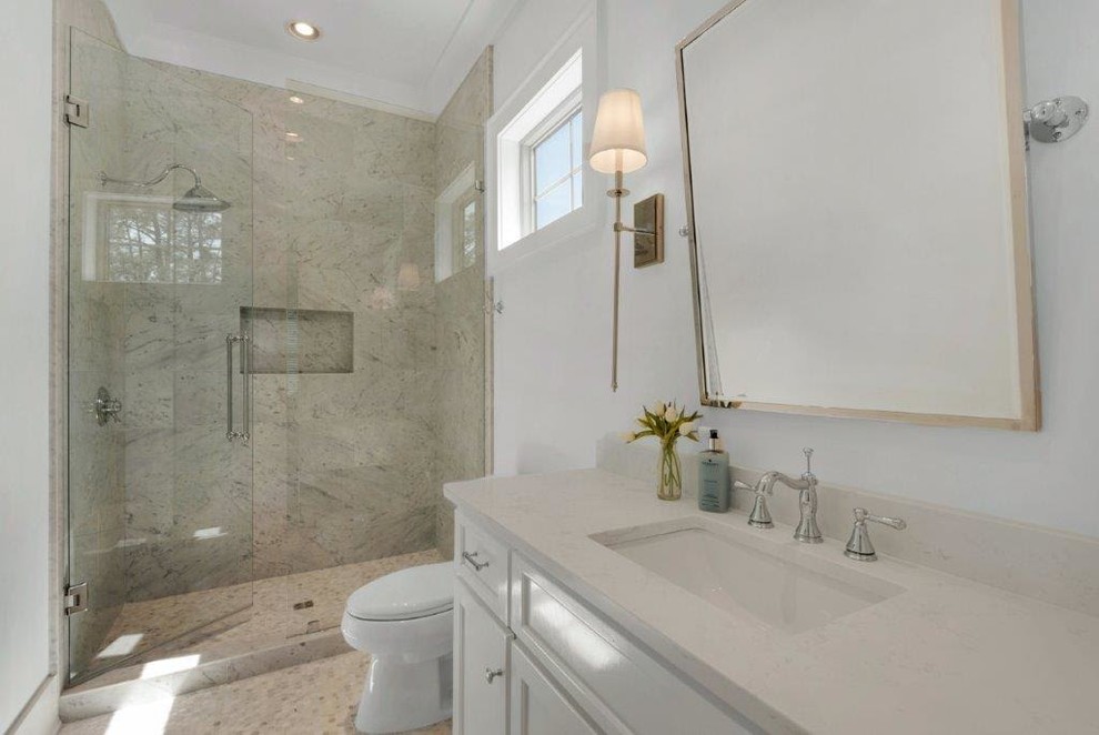 Photo of a mid-sized country 3/4 bathroom in Miami with shaker cabinets, white cabinets, an alcove shower, a two-piece toilet, beige tile, stone tile, white walls, mosaic tile floors, an undermount sink, engineered quartz benchtops, beige floor and a hinged shower door.