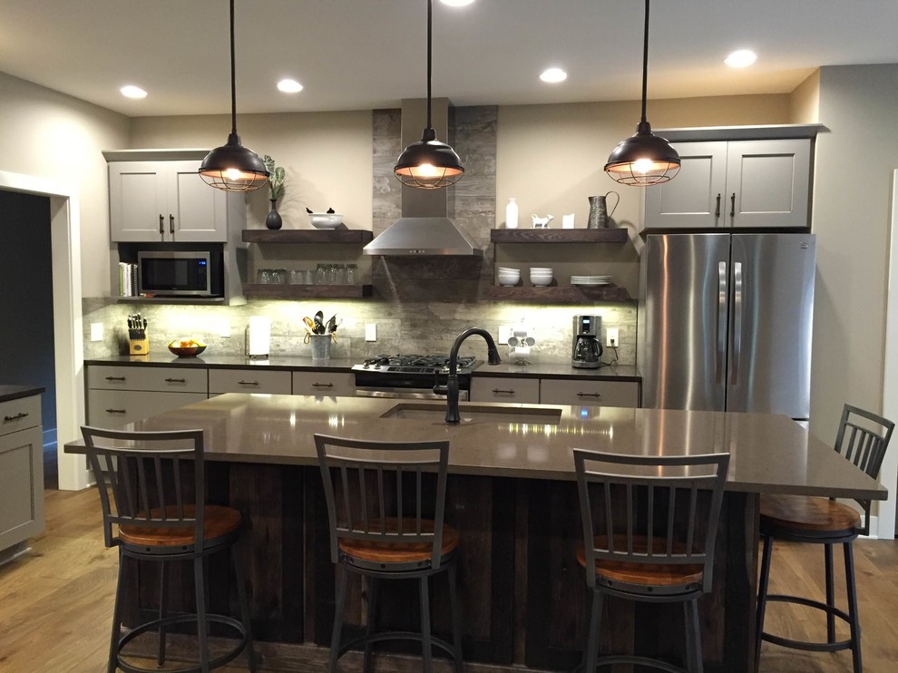 Inspiration for a large transitional l-shaped dark wood floor and brown floor open concept kitchen remodel in Grand Rapids with an island, an undermount sink, shaker cabinets, gray cabinets, quartzite countertops, brown backsplash, wood backsplash, stainless steel appliances and gray countertops