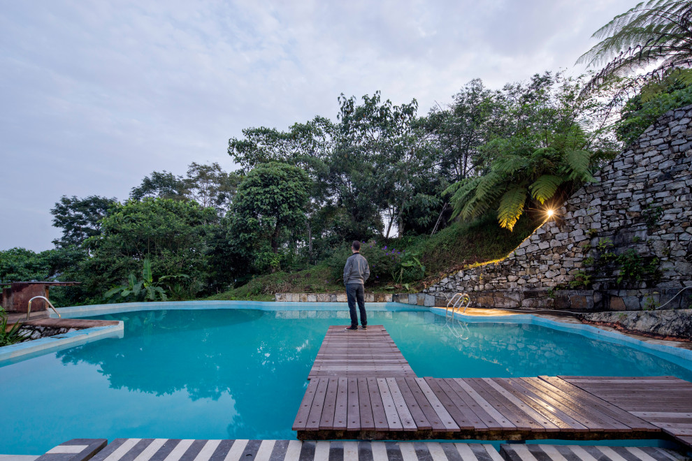 Идея дизайна: большой естественный ландшафтный бассейн произвольной формы на заднем дворе в стиле рустика с покрытием из бетонных плит