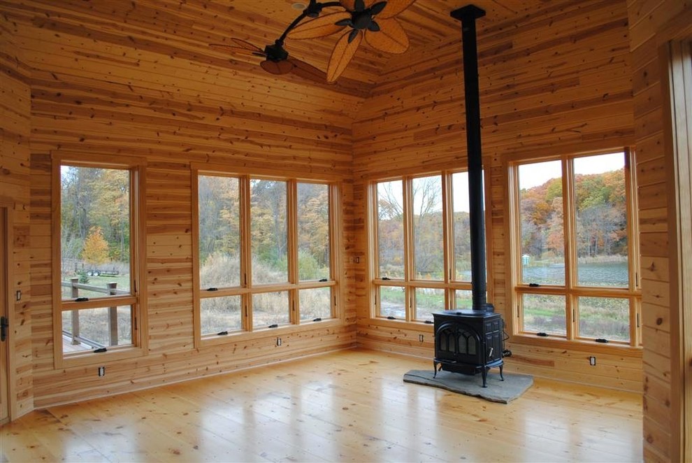 Country living room in Chicago with light hardwood floors and a wood stove.