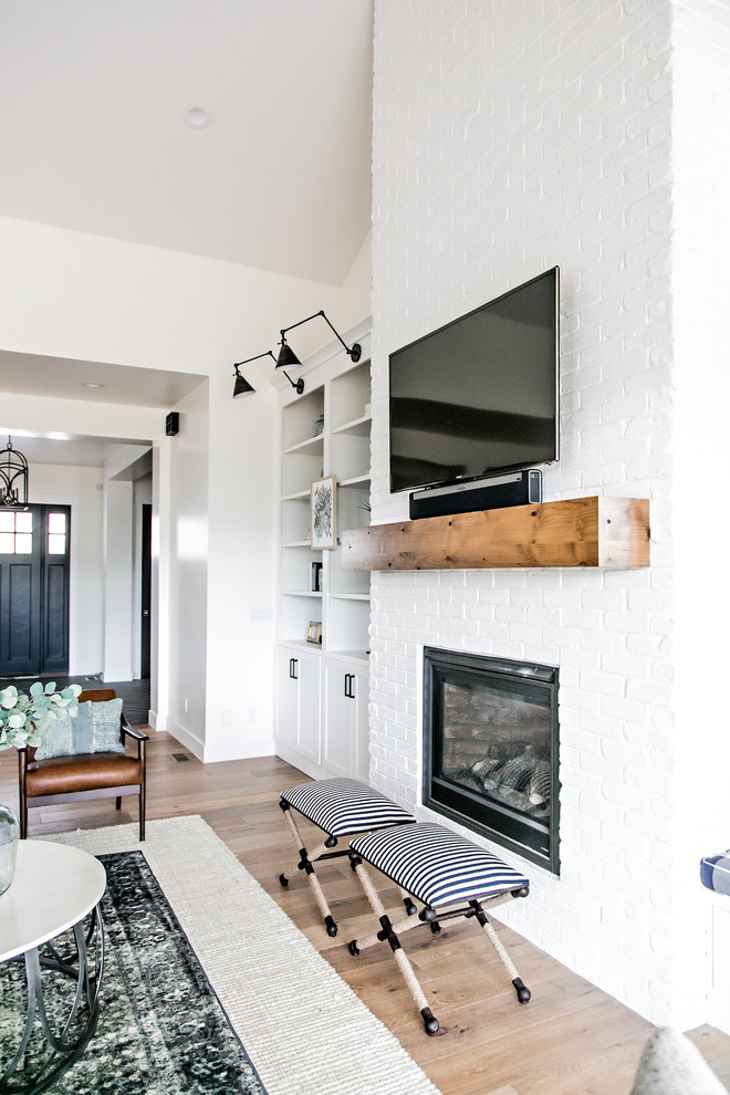 Living room - mid-sized farmhouse formal and open concept medium tone wood floor and brown floor living room idea in Salt Lake City with white walls, a standard fireplace, a brick fireplace and a wall-mounted tv