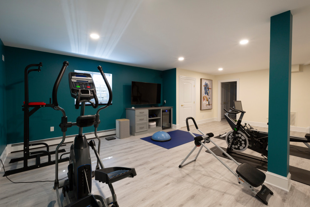 This is an example of a large transitional home weight room in New York with blue walls, laminate floors and grey floor.