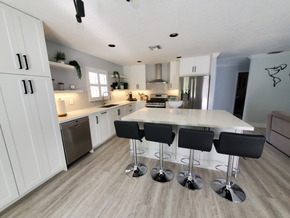 Example of a large transitional l-shaped kitchen pantry design in Miami with shaker cabinets, white cabinets, quartz countertops and an island