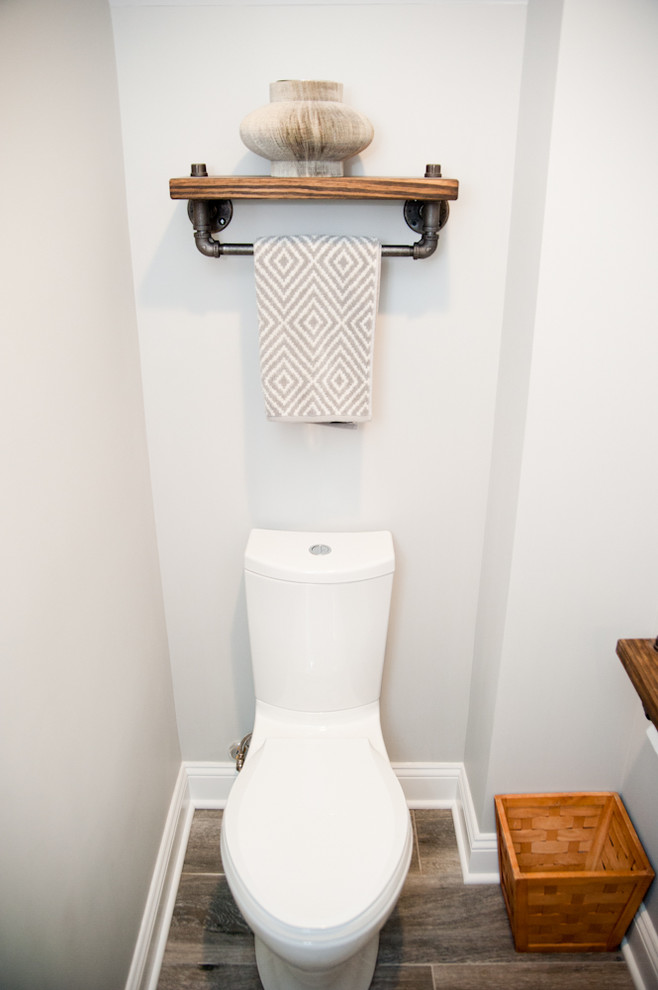 Photo of a small contemporary powder room in New York with a vessel sink, wood benchtops, a one-piece toilet, grey walls and medium hardwood floors.