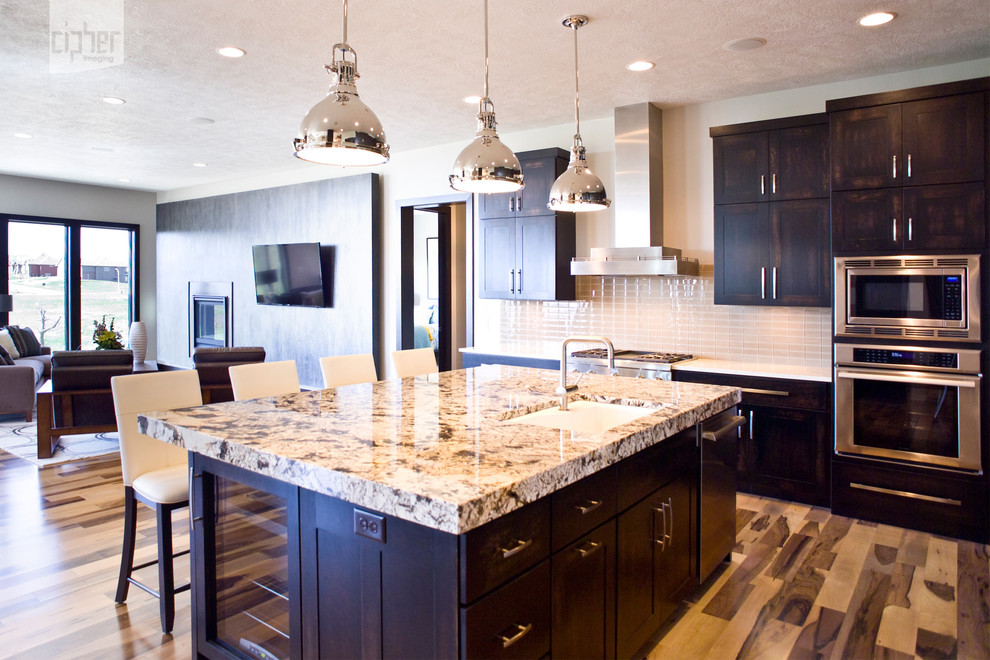 Eat-in kitchen - large transitional l-shaped medium tone wood floor and multicolored floor eat-in kitchen idea with an undermount sink, dark wood cabinets, stainless steel appliances, white walls, an island, raised-panel cabinets, granite countertops, beige backsplash and porcelain backsplash