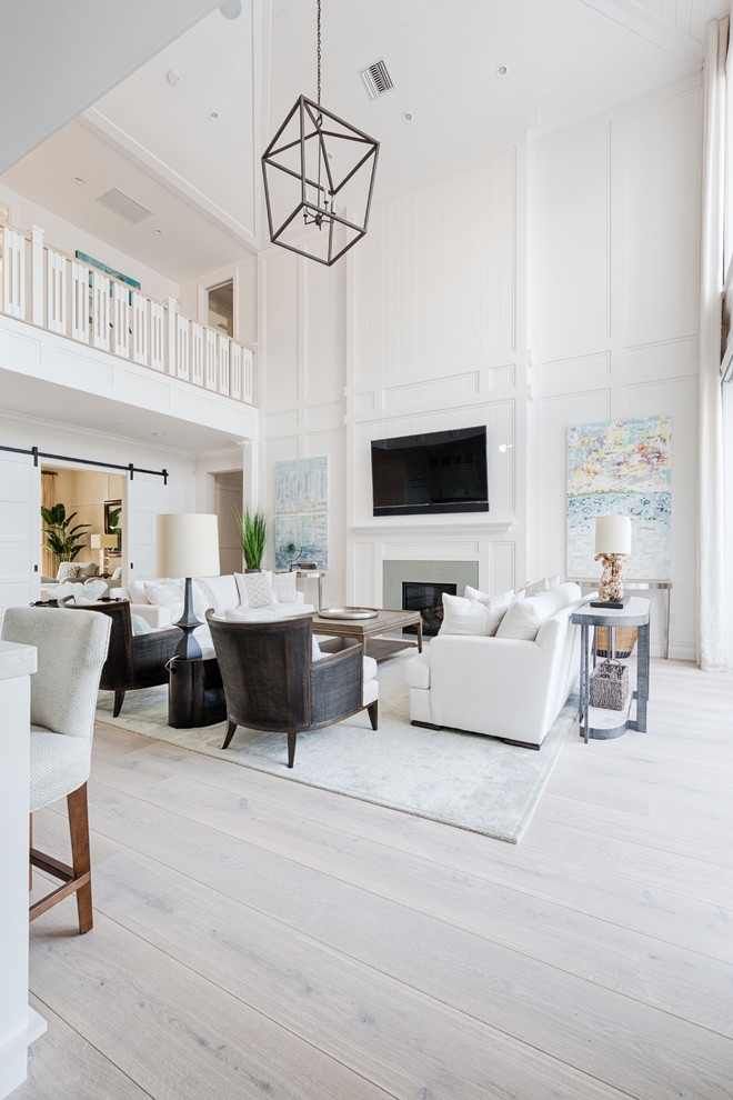 Example of a mid-sized transitional open concept light wood floor and beige floor family room design in Miami with white walls, a standard fireplace, a tile fireplace and a wall-mounted tv