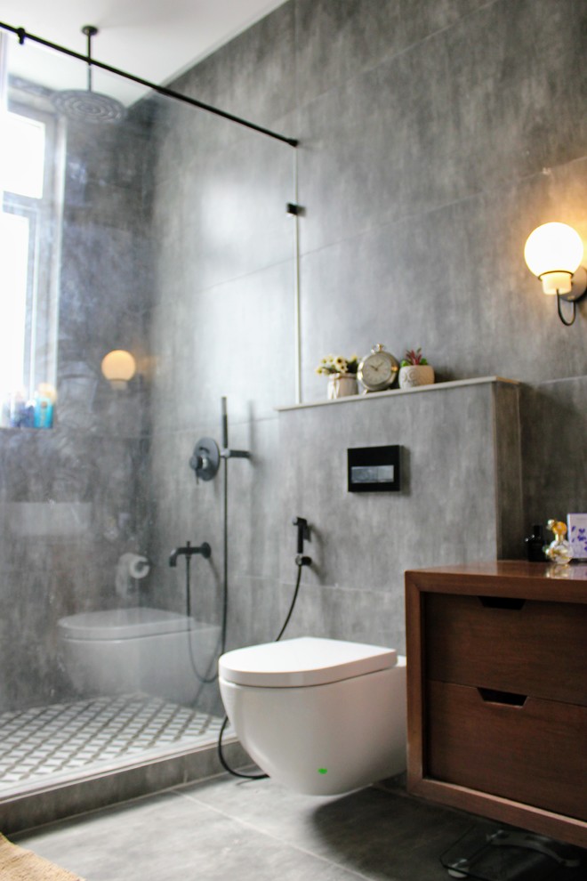 Mid-sized industrial master bathroom in Delhi with furniture-like cabinets, medium wood cabinets, an alcove shower, a wall-mount toilet, gray tile, cement tile, grey walls, cement tiles, a console sink, wood benchtops, grey floor, a hinged shower door and brown benchtops.