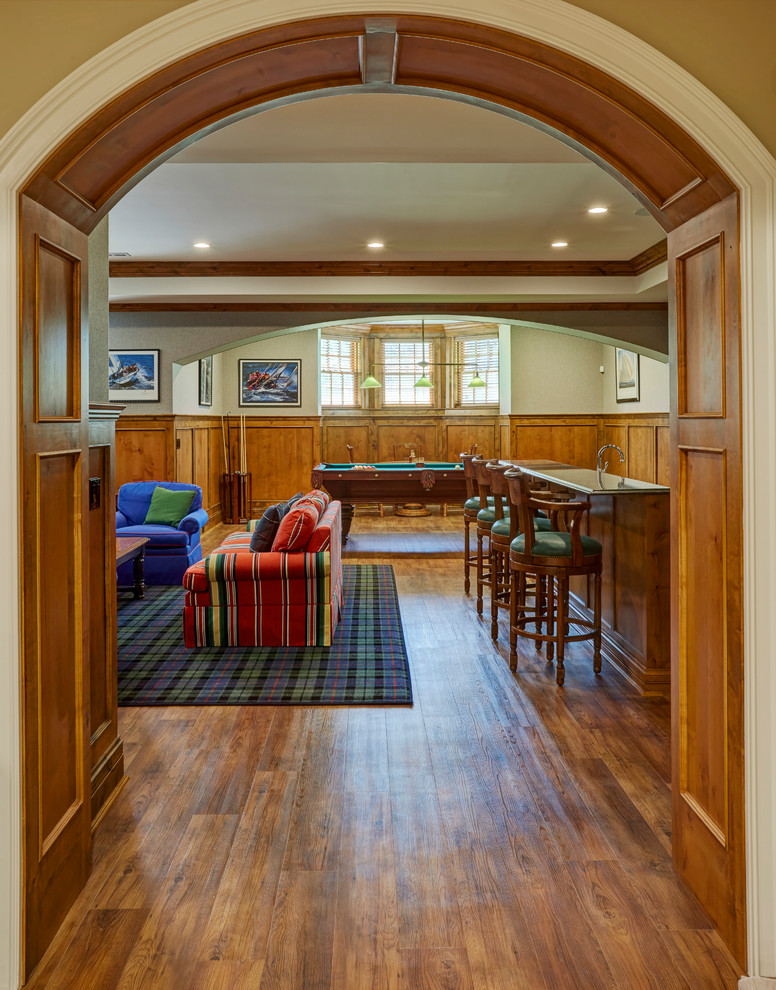 This is an example of an expansive traditional look-out basement in Milwaukee with green walls, laminate floors and brown floor.