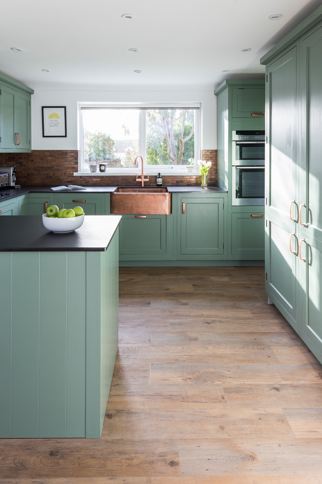 Photo of a mid-sized traditional u-shaped eat-in kitchen in Kent with a farmhouse sink, shaker cabinets, green cabinets, quartz benchtops, metal splashback, linoleum floors, a peninsula and green floor.