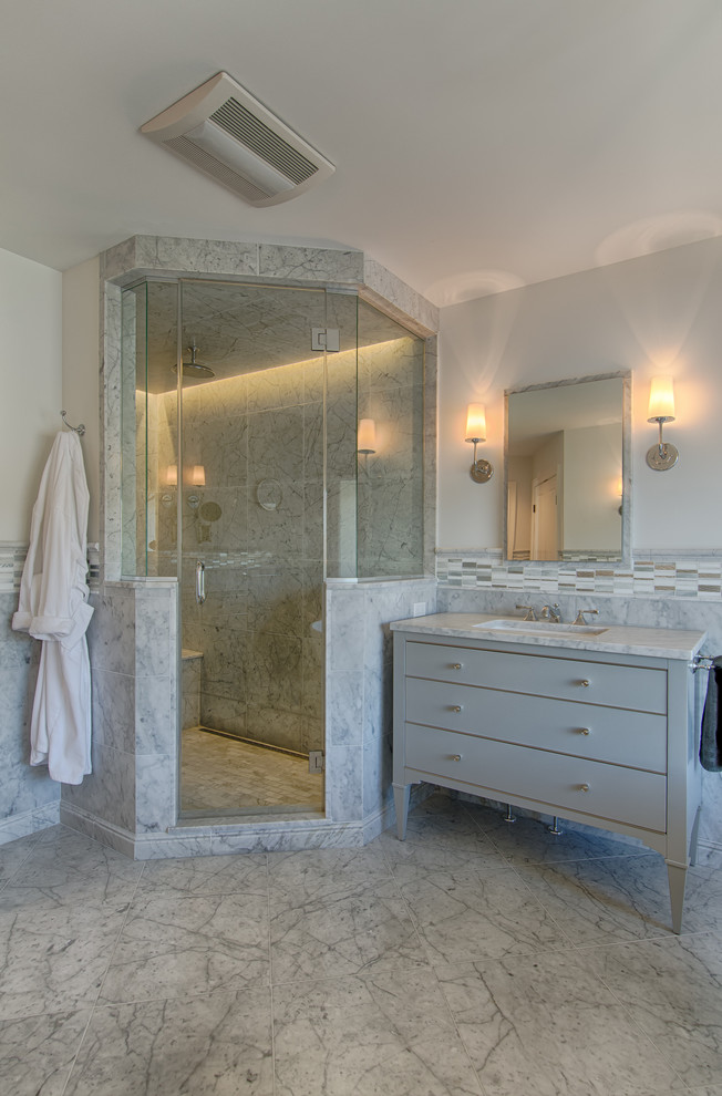 This is an example of a mid-sized transitional bathroom in New York with flat-panel cabinets, grey cabinets, a freestanding tub, a one-piece toilet, gray tile, glass tile, grey walls, marble floors, an undermount sink, marble benchtops, with a sauna and a corner shower.