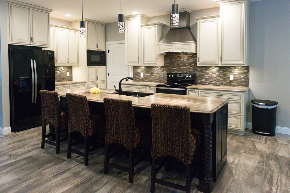 Large transitional l-shaped ceramic tile eat-in kitchen photo in Chicago with an undermount sink, raised-panel cabinets, dark wood cabinets, marble countertops, brown backsplash, glass tile backsplash, black appliances and an island