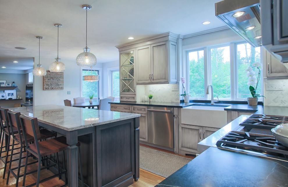 Expansive transitional u-shaped eat-in kitchen in Boston with a farmhouse sink, recessed-panel cabinets, grey cabinets, quartz benchtops, white splashback, stainless steel appliances, light hardwood floors and with island.