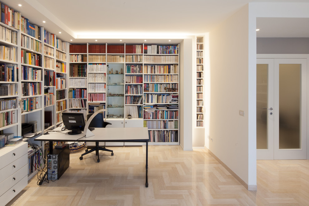 This is an example of a medium sized modern home office in Venice with light hardwood flooring.