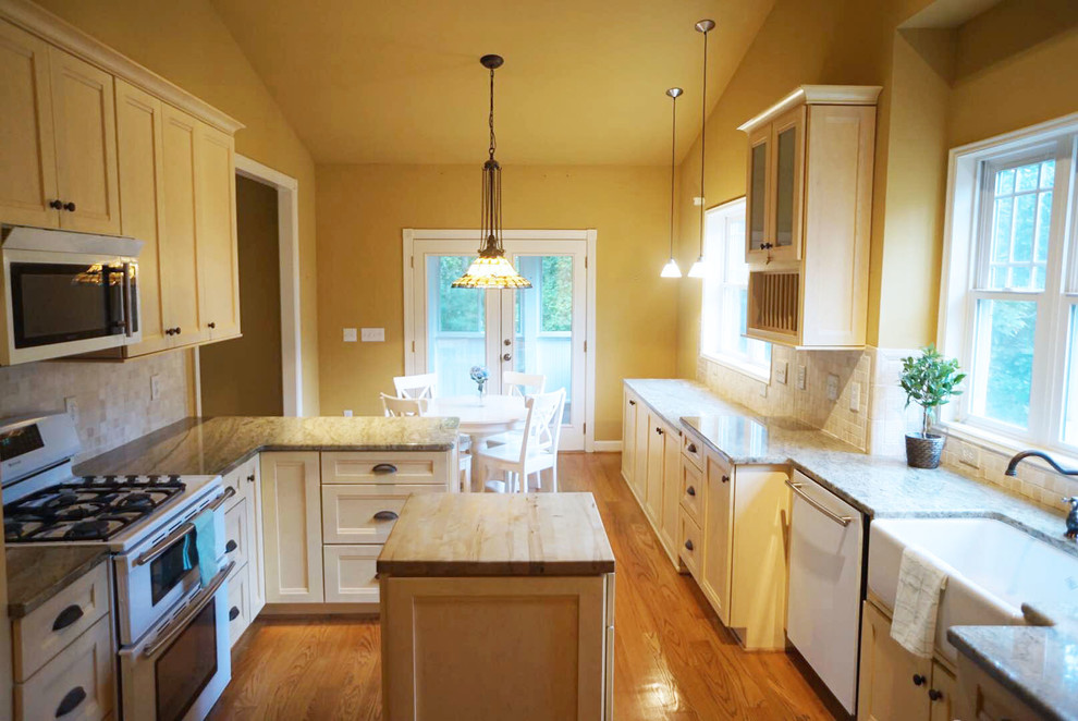 Inspiration for a large traditional galley eat-in kitchen in Raleigh with shaker cabinets, yellow cabinets, stone tile splashback, white appliances, light hardwood floors and with island.