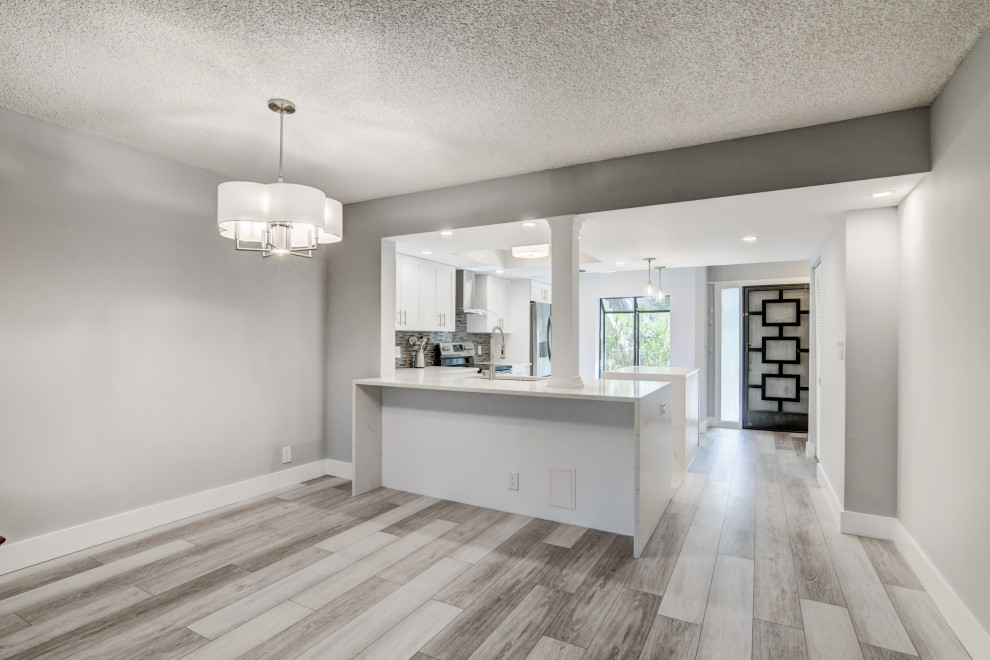 Immagine di una sala da pranzo aperta verso la cucina chic di medie dimensioni con pareti grigie, pavimento in laminato, pavimento grigio e soffitto a cassettoni