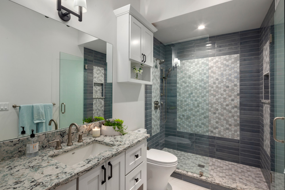 This is an example of a transitional bathroom in Other with shaker cabinets, white cabinets, an alcove shower, gray tile, an undermount sink, grey floor, a hinged shower door, grey benchtops and a freestanding vanity.