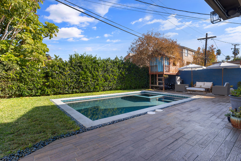 Foto di una piscina monocorsia moderna rettangolare di medie dimensioni e dietro casa con una vasca idromassaggio e pavimentazioni in cemento