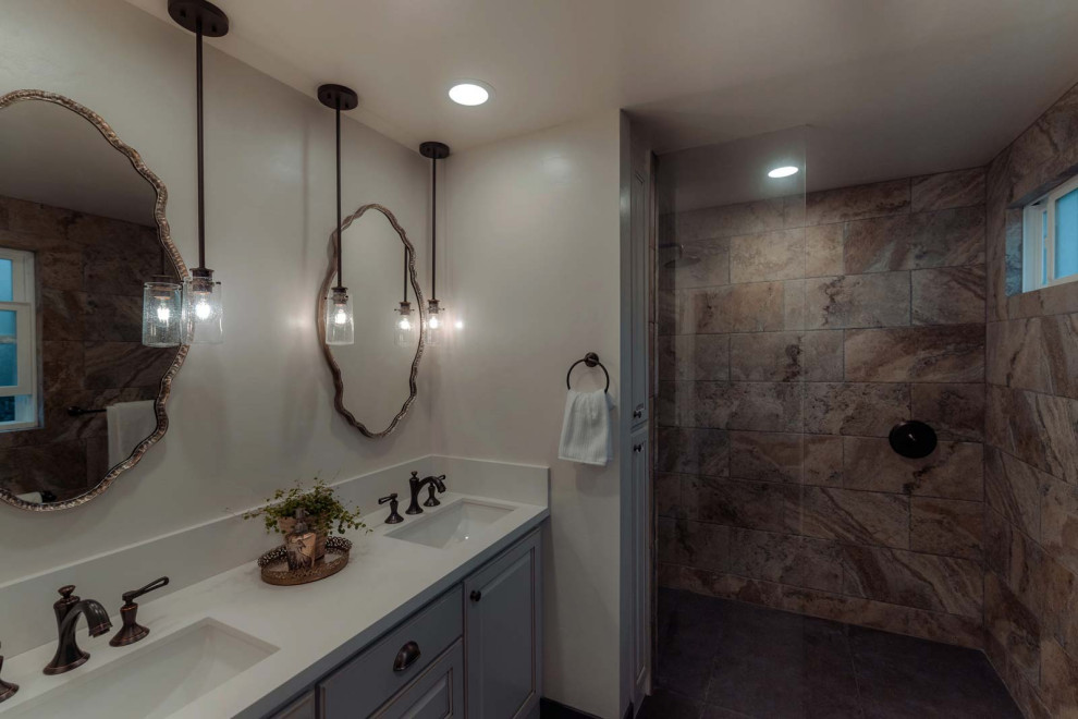Photo of a modern bathroom in Los Angeles with a shower/bathtub combo, a one-piece toilet, white tile, porcelain tile, blue walls, porcelain floors, an undermount sink, grey floor, a hinged shower door and white benchtops.