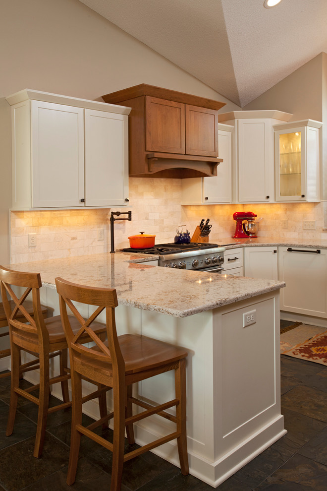 Inspiration for a mid-sized transitional u-shaped slate floor eat-in kitchen remodel in Minneapolis with a farmhouse sink, raised-panel cabinets, white cabinets, quartz countertops, beige backsplash, subway tile backsplash, paneled appliances and a peninsula