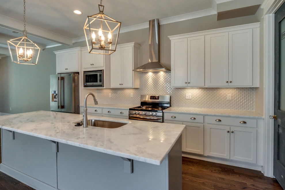 Mid-sized arts and crafts single-wall eat-in kitchen in Nashville with an undermount sink, shaker cabinets, white cabinets, granite benchtops, white splashback, porcelain splashback, stainless steel appliances, medium hardwood floors, with island, brown floor and grey benchtop.