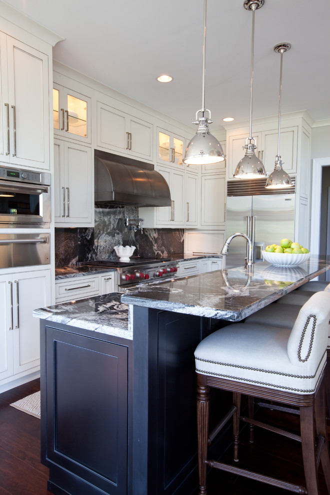 Mid-sized traditional l-shaped eat-in kitchen in Baltimore with shaker cabinets, white cabinets, granite benchtops, black splashback, stone slab splashback, stainless steel appliances, dark hardwood floors, with island, brown floor and multi-coloured benchtop.