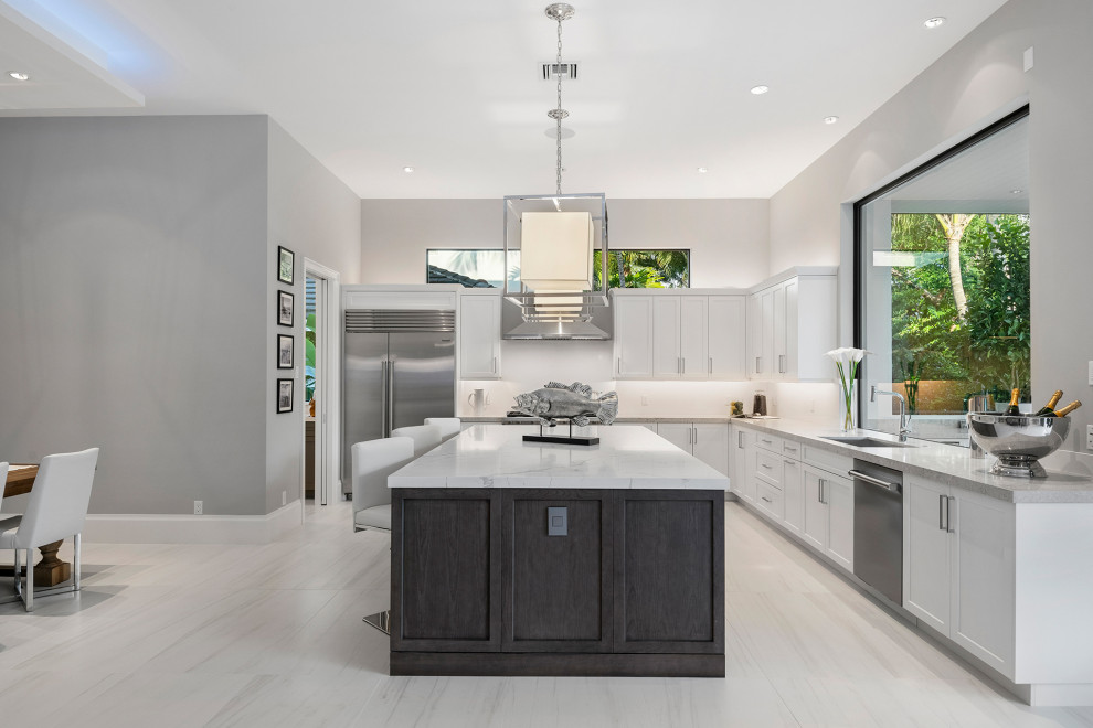 Large contemporary l-shaped open plan kitchen in Miami with an undermount sink, flat-panel cabinets, light wood cabinets, quartz benchtops, white splashback, engineered quartz splashback, stainless steel appliances, porcelain floors, with island, white floor, white benchtop and coffered.