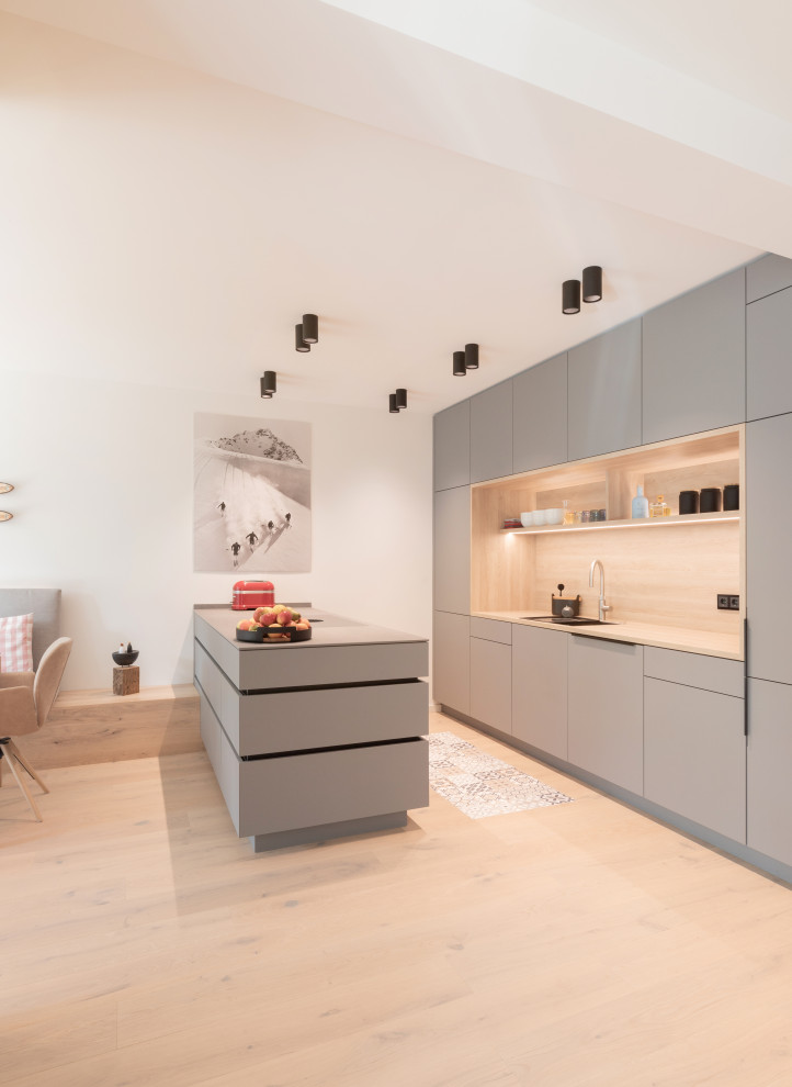 Mid-sized scandinavian single-wall eat-in kitchen in Other with a drop-in sink, flat-panel cabinets, grey cabinets, solid surface benchtops, beige splashback, timber splashback, medium hardwood floors, with island, brown floor and grey benchtop.