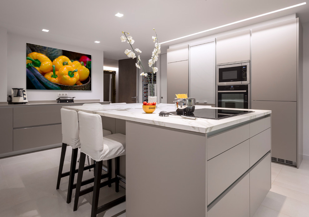 Large contemporary u-shaped open plan kitchen in Barcelona with a double-bowl sink, flat-panel cabinets, beige cabinets, stainless steel appliances, ceramic floors, with island and beige floor.