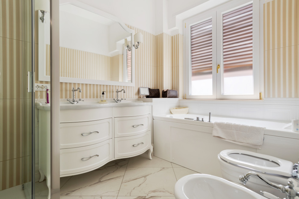 This is an example of a mid-sized traditional master bathroom in Rome with furniture-like cabinets, white cabinets, a hot tub, a corner shower, a bidet, gray tile, matchstick tile, yellow walls, porcelain floors, a console sink, multi-coloured floor, a hinged shower door, white benchtops, a double vanity, a freestanding vanity and decorative wall panelling.