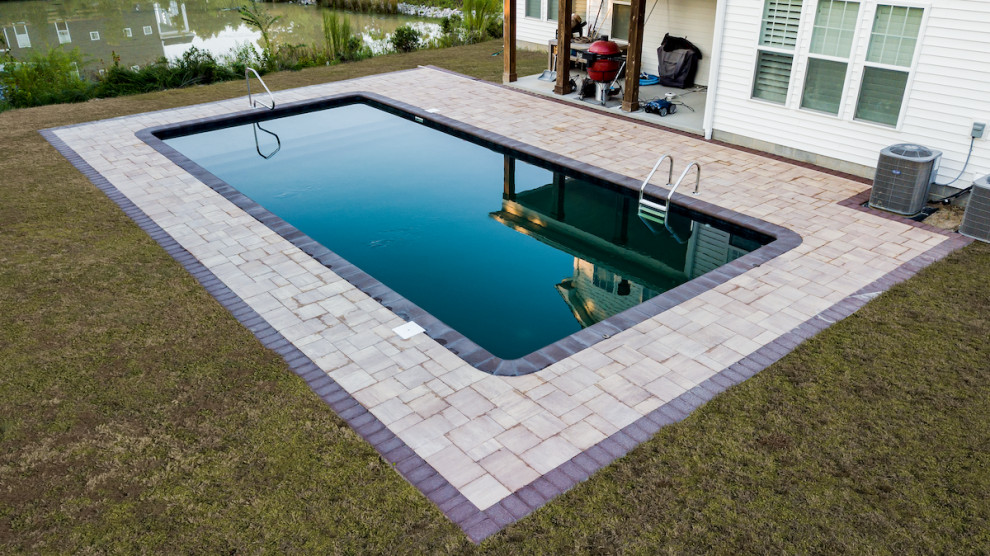 Large modern back rectangular lengths swimming pool in Other with with pool landscaping and brick paving.