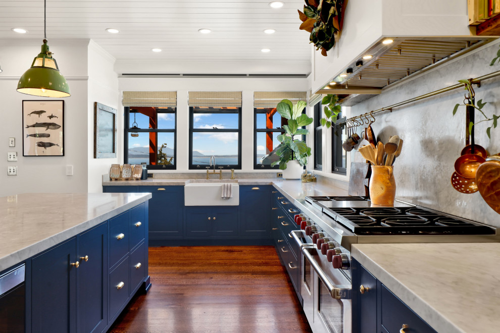 Photo of a large classic l-shaped kitchen/diner in Seattle with a single-bowl sink, flat-panel cabinets, blue cabinets, marble worktops, grey splashback, marble splashback, stainless steel appliances, light hardwood flooring, an island, orange floors, white worktops and a wood ceiling.