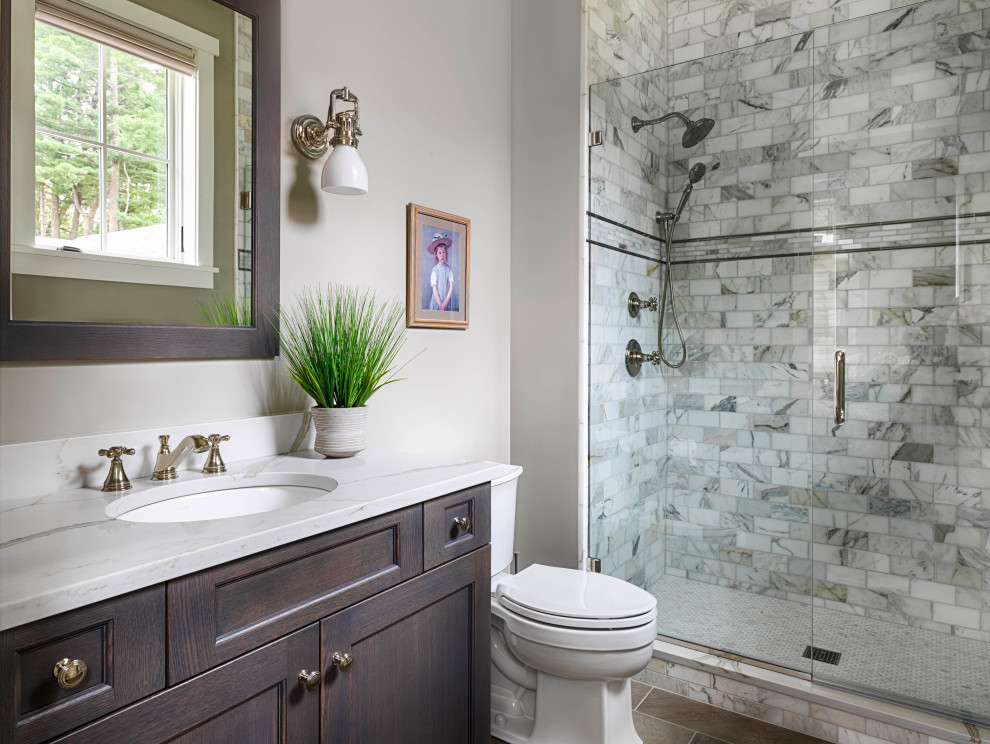 Mid-sized transitional 3/4 bathroom with dark wood cabinets, an alcove shower, gray tile, grey walls, an undermount sink, grey floor, a hinged shower door, grey benchtops, a single vanity, a built-in vanity, a two-piece toilet, porcelain floors and marble benchtops.