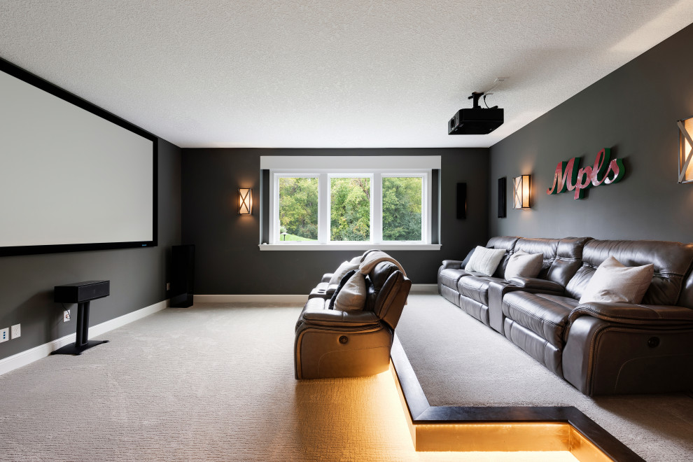 Photo of a mid-sized traditional enclosed home theatre in Minneapolis with black walls, carpet, a projector screen and beige floor.
