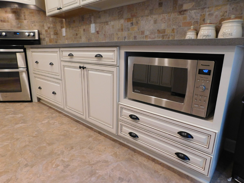 Enclosed kitchen - mid-sized transitional galley vinyl floor enclosed kitchen idea with a farmhouse sink, raised-panel cabinets, beige cabinets, solid surface countertops, multicolored backsplash, stone tile backsplash, stainless steel appliances and no island