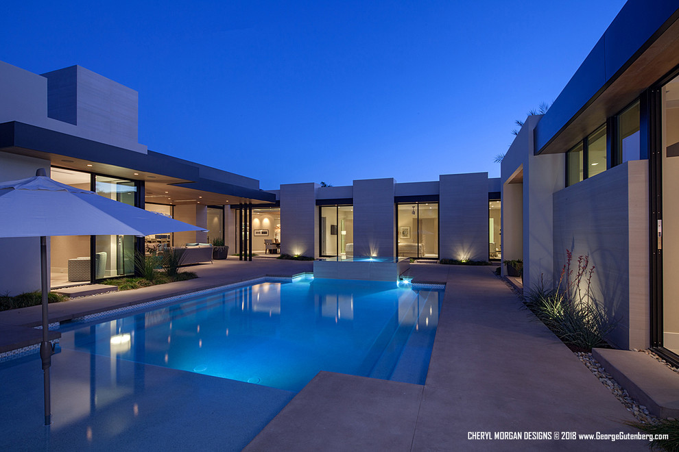 Expansive contemporary courtyard rectangular infinity pool in Los Angeles with a hot tub and concrete slab.