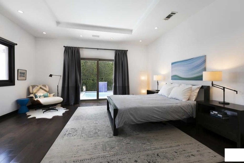 This is an example of a mid-sized mediterranean master bedroom in Los Angeles with white walls, dark hardwood floors and brown floor.