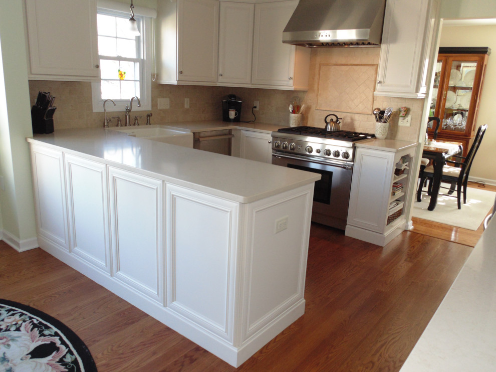 Large transitional u-shaped medium tone wood floor and brown floor eat-in kitchen photo with a farmhouse sink, flat-panel cabinets, white cabinets, quartz countertops, beige backsplash, travertine backsplash, stainless steel appliances and beige countertops